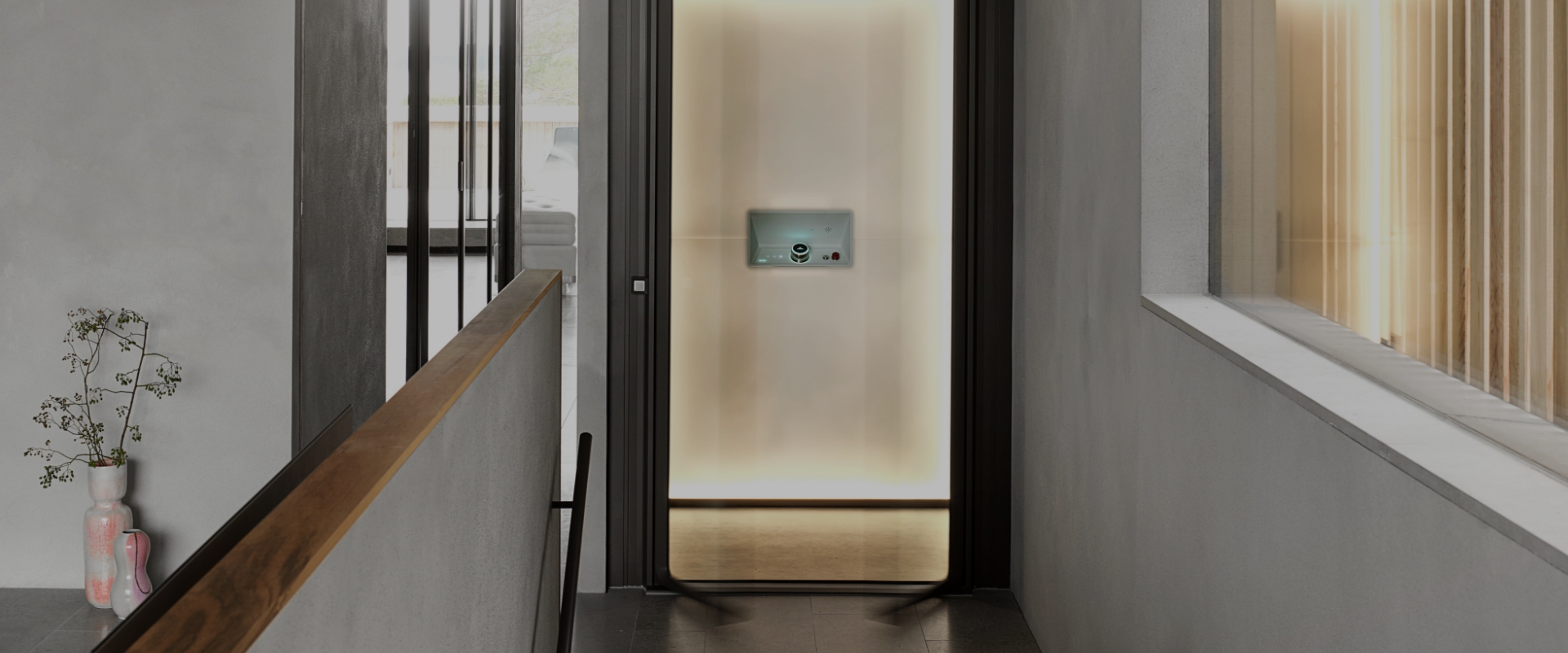 Blick von einem Flur in einen modernen, warm ausgeleuchteten Fahrstuhl in einem privaten Haus