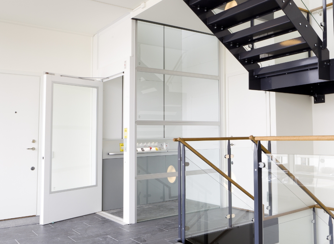 Weiträumiger Flur in einem öffentlichen Gebäude mit moderner Treppe und weißem Fahrstuhl
